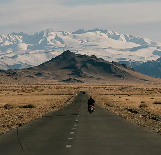 Men riding bike on empty road near mountain hills