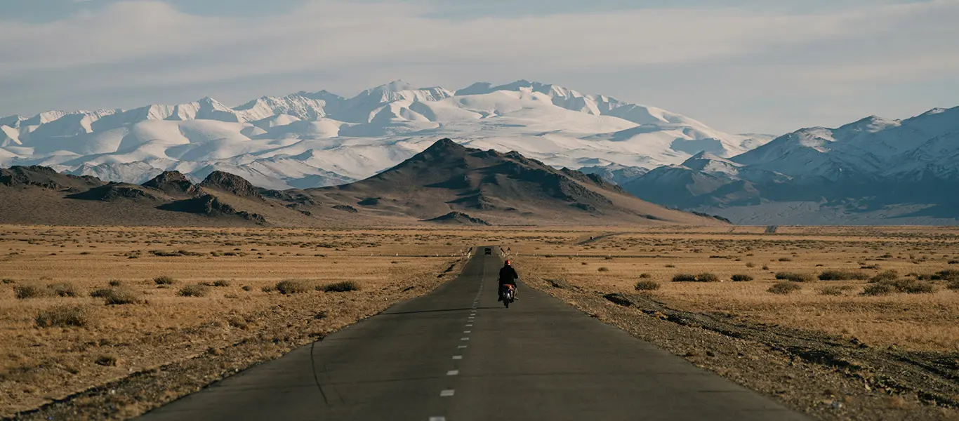 Men riding bike on empty road near mountain hills