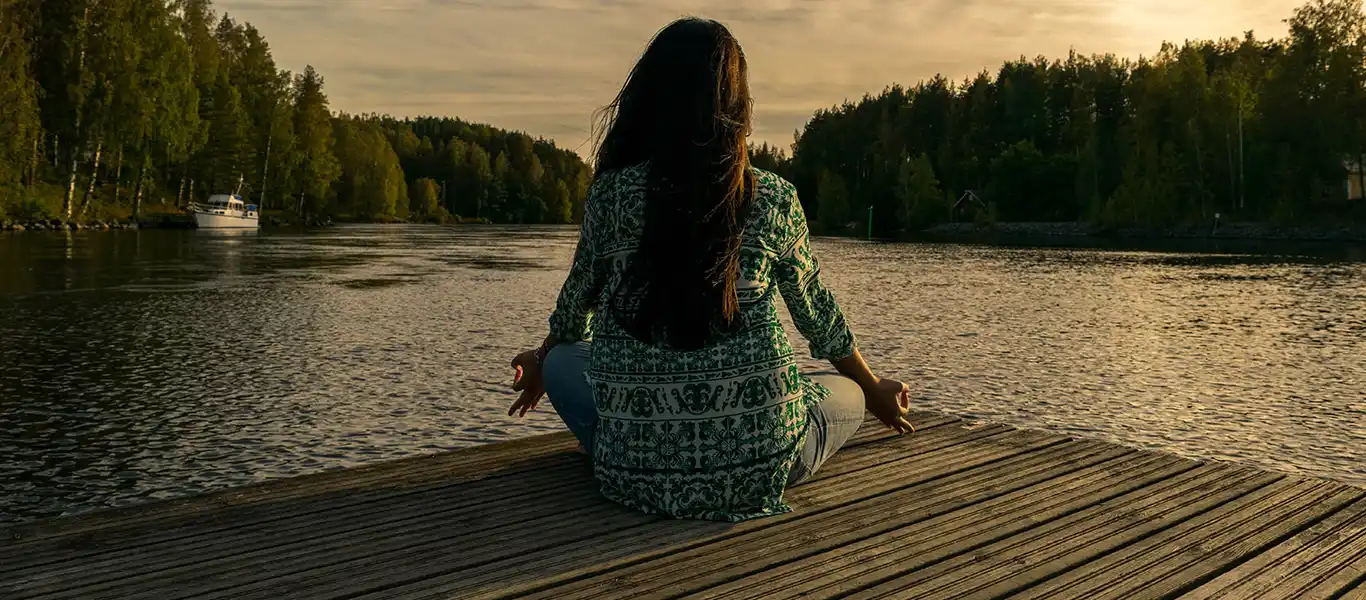 Girl doing meditation on the river bank